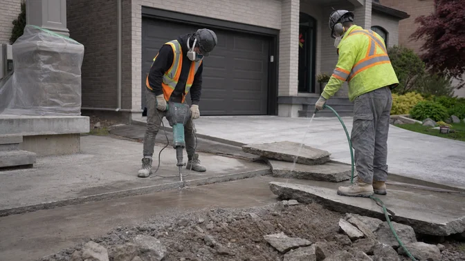 Crew breaking and wetting a concrete driveway for removal