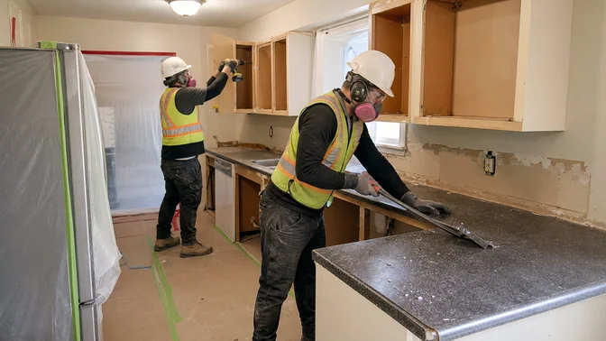 Crew removing kitchen cabinetry and countertops